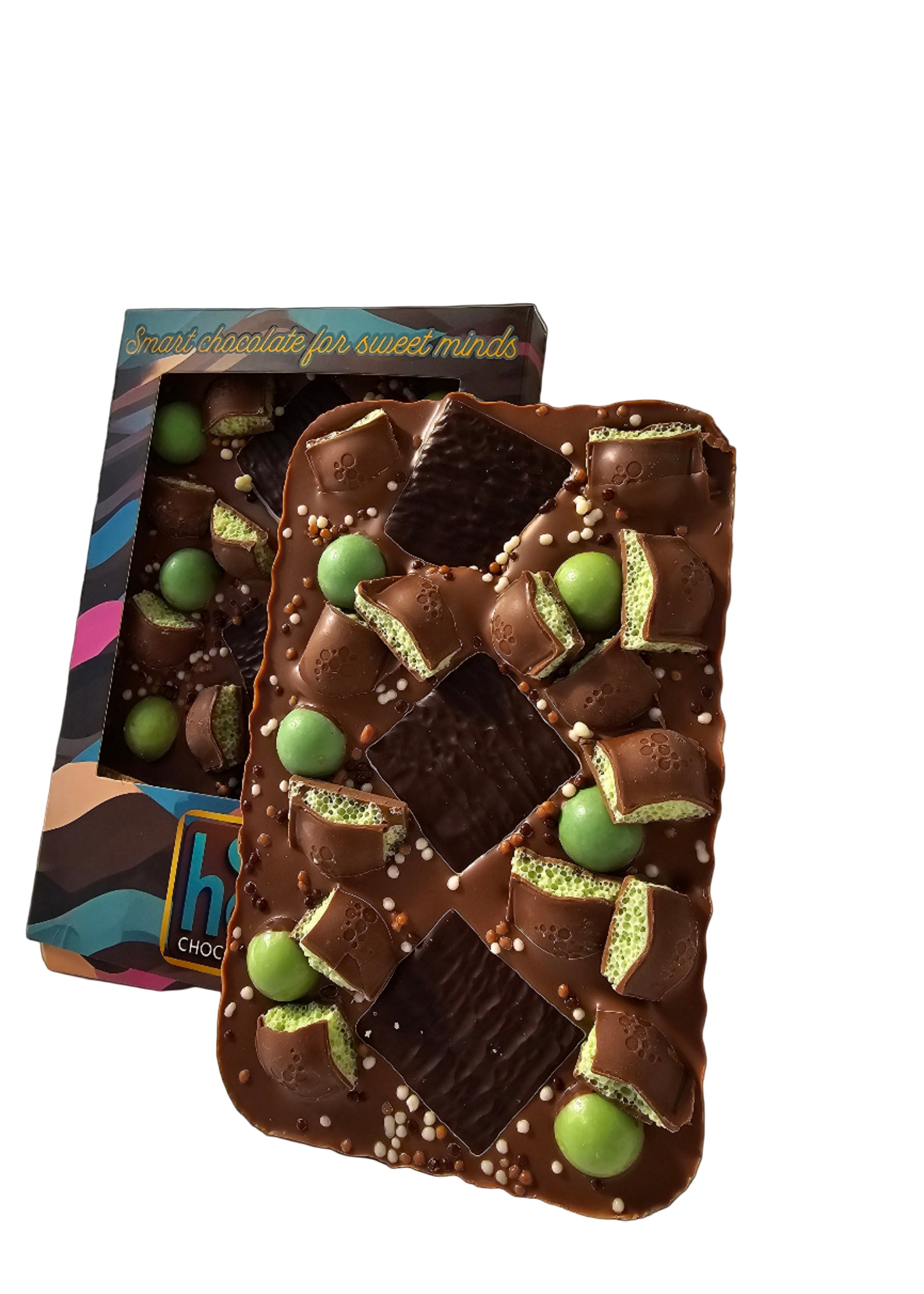 Chocolate bar with green mint candies and packaging on a black background